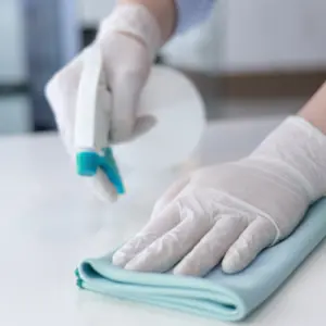 Close-up of hands sanitizing a surface, demonstrating professional sanitization service.